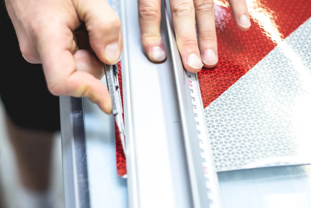 Mitarbeiter schneidet Warnmarkierung zurecht